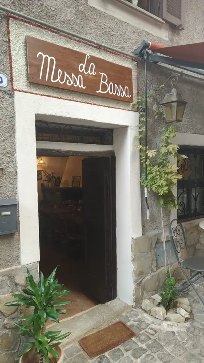 L'insegna in legno de La Messa Bassa sopra il portone, in Via del Castello