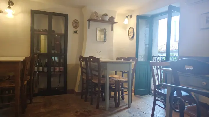 La saletta rialzata con la vetrina dei vini e la porta verde sul balcone