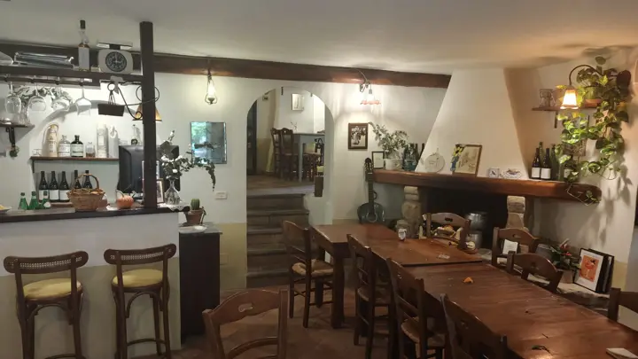 La sala del camino con le tavolate in legno e il bancone